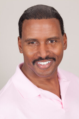 Approachable man with a bright smile and neat mustache, wearing a pink polo shirt for a casual studio headshot, from Ken Weingart's Los Angeles headshots portfolio.
