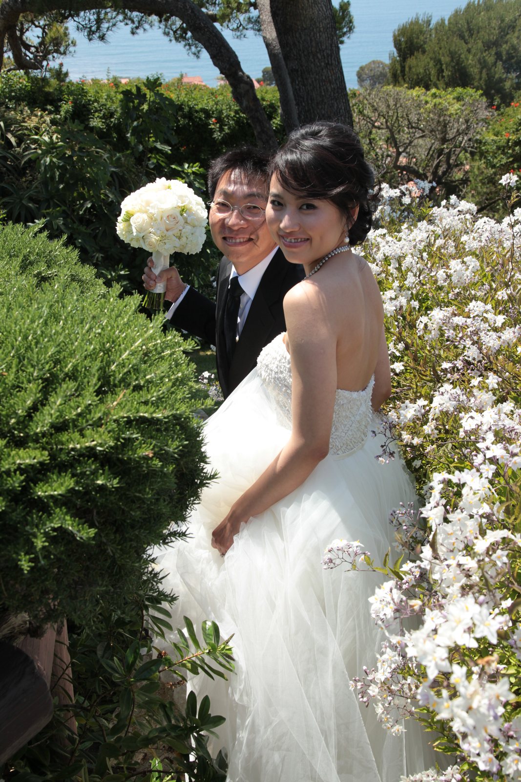 Bride and groom portrait among flowers overlooking the coast